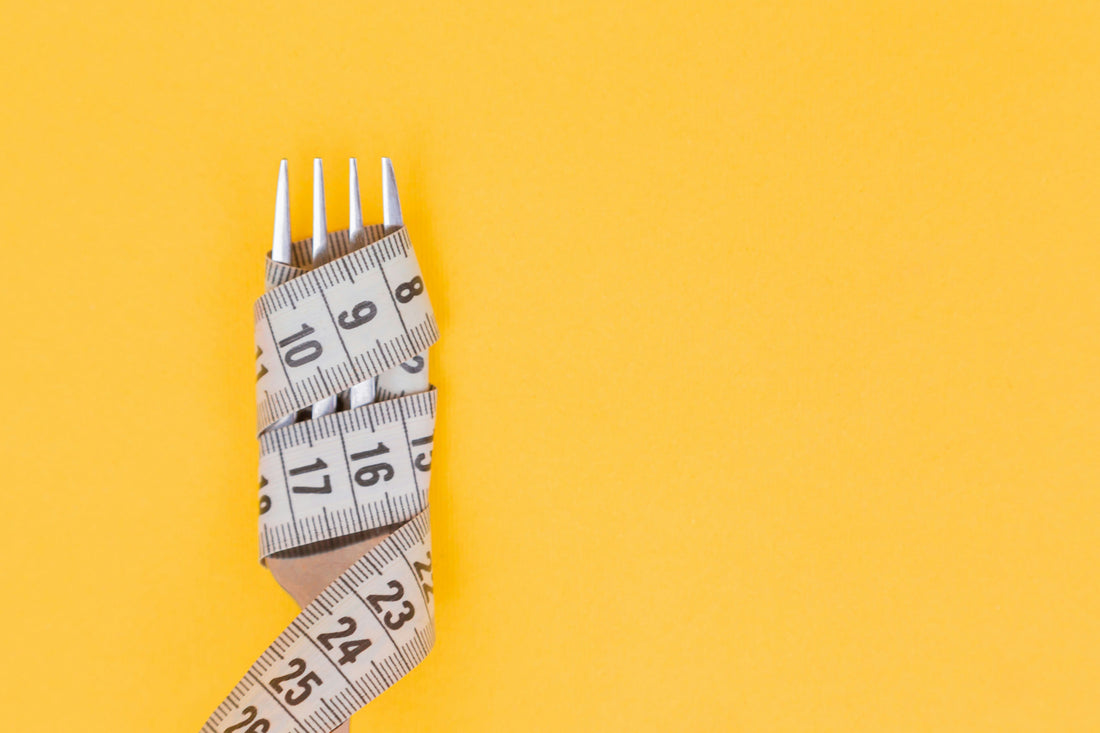 fork on yellow background wrapped in a measuring tape