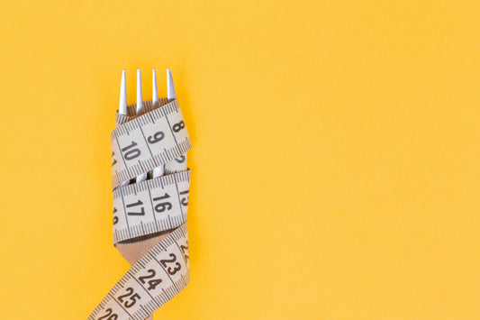 fork on yellow background wrapped in a measuring tape