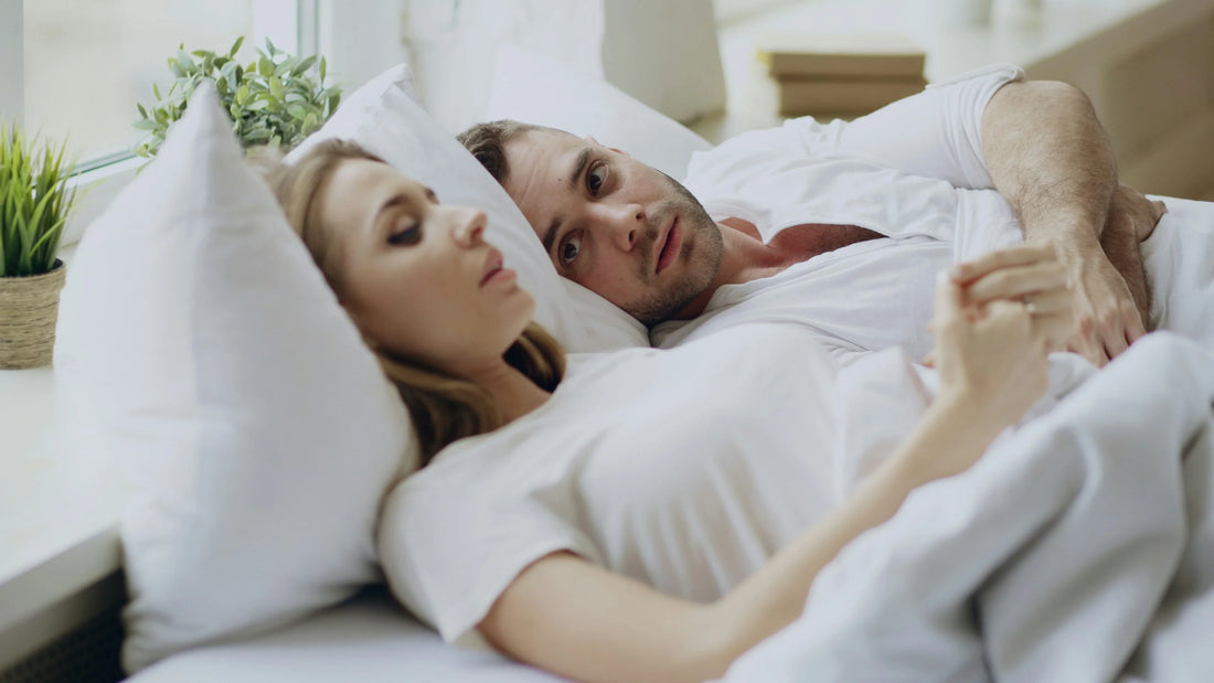 Couple looking discontent laying in bed